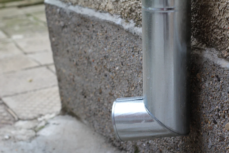 Galvanized downspout elbow at the base of a masonry wall